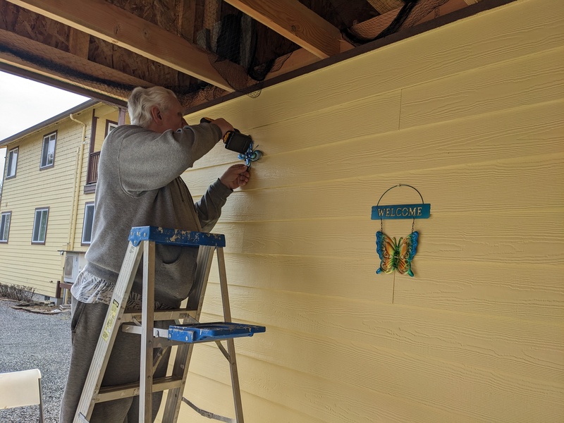 Don adds screws to hold more of Lois's decorations.