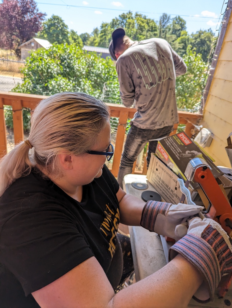 Larissa at the belt sander, Josiah.