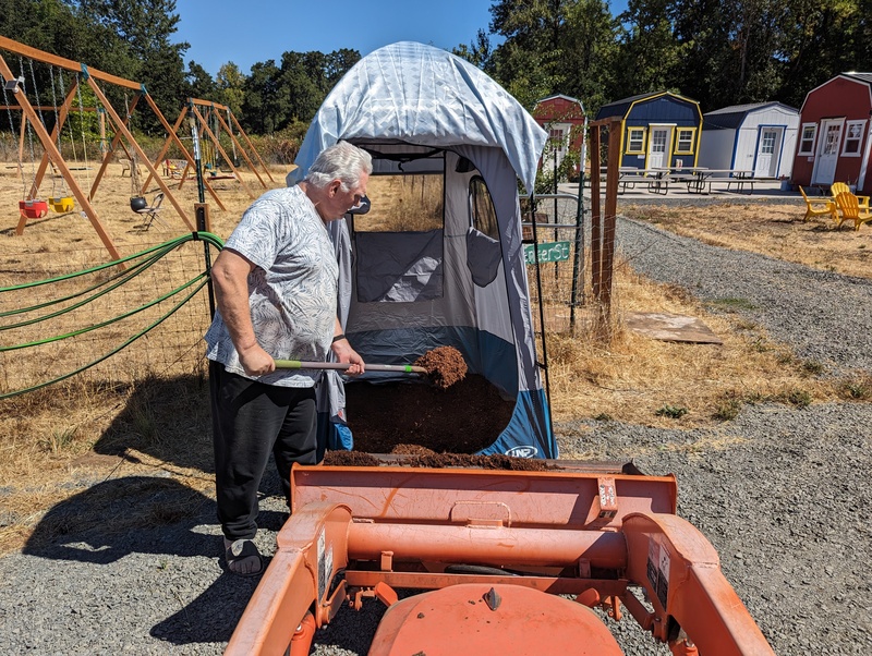 Don puts down bark dust in the pottie tent.