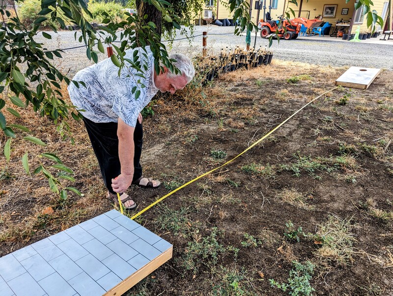 Don measuring how far apart the cornhole boards are.