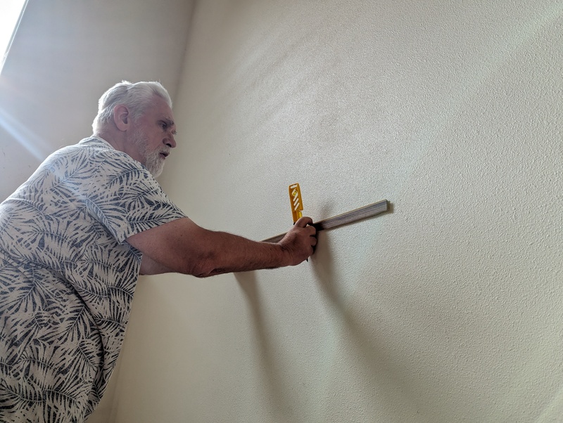 Don measuring and leveling the wall for hanging the canvas.