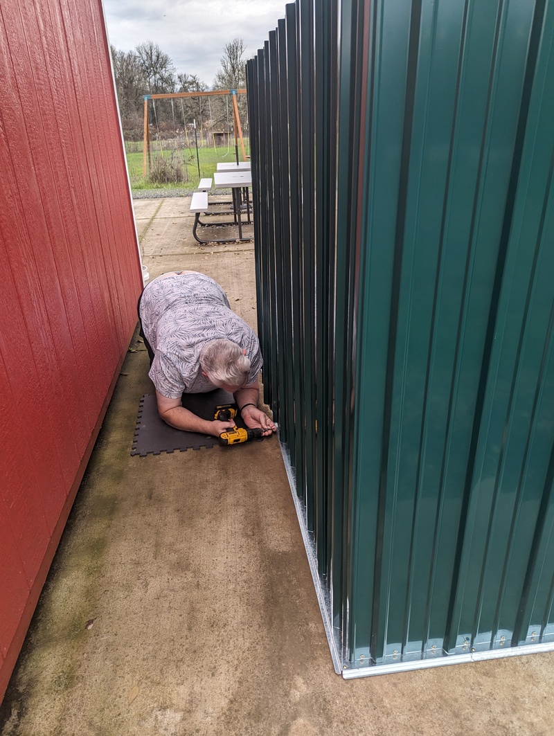 Don putting together the garden shed storage structure for outdoor games and firepit village things.