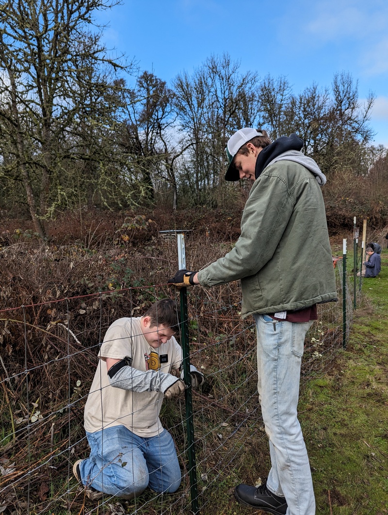 Elder Kunz and Elder Nielson work on clipping the fence to the t-posts.