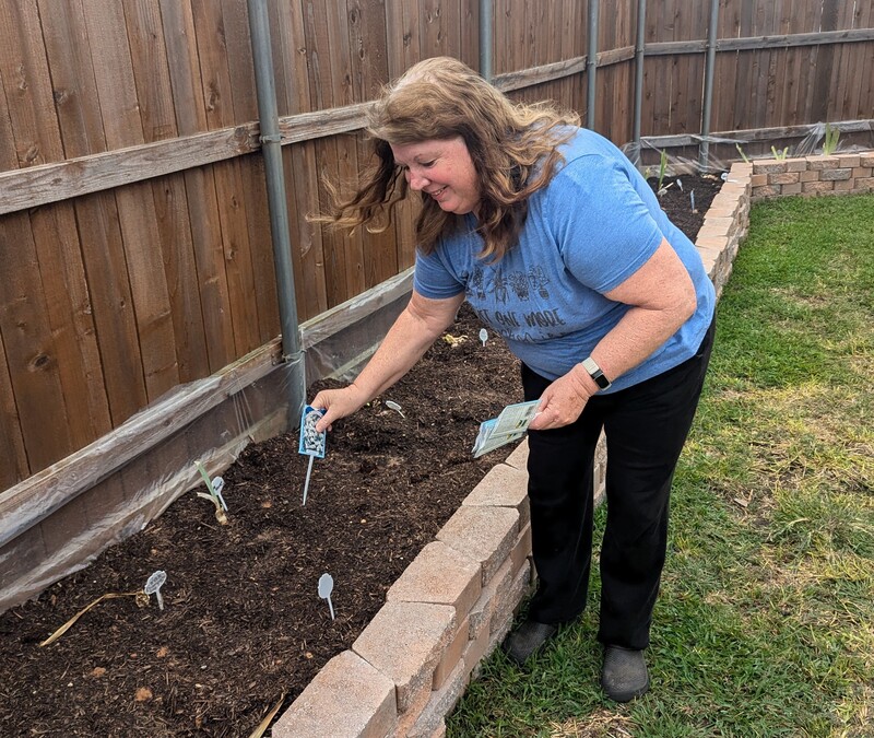 Lois planting labels around the flower seeds.