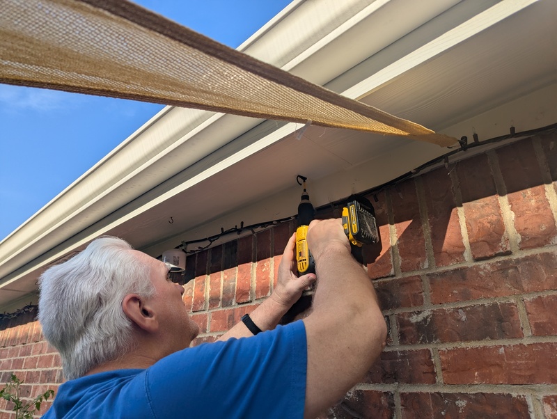 Don installing a sunblock tarp. The hooks later bent out straight in the wind.
