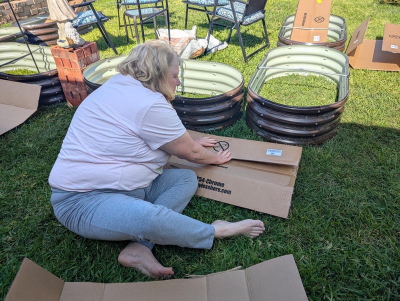 Lois put cardboard at the bottom of all the raised bed garden cells to reduce the growth of grass in the cells.