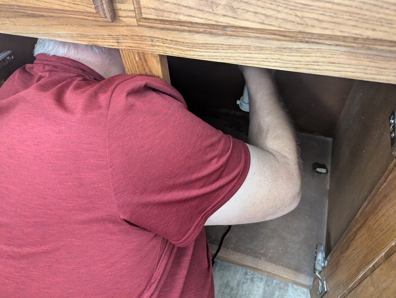 Don working to clean out his sink trap because the drain was flowing so slowly.