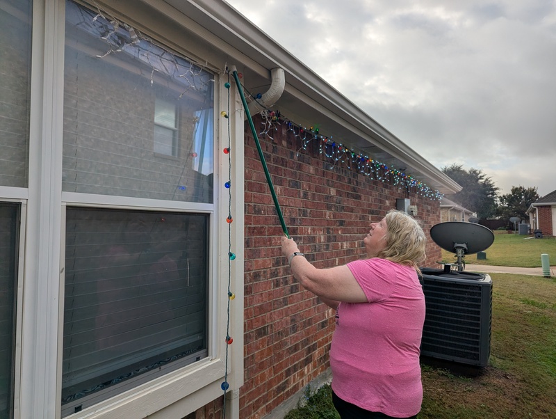 Lois putting up Christmas lights.