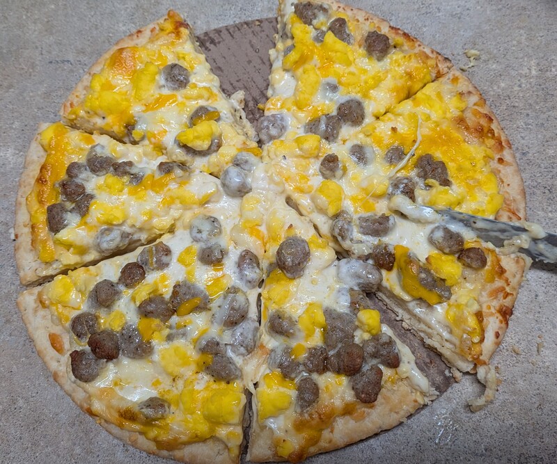 Pi Day breakfast eggs, sausage, and cheese pizza with biscuit crust and country gravy sauce.